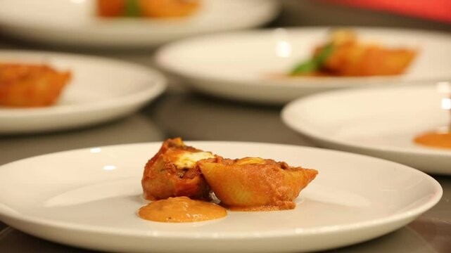 Chef stirs seasoned minced meat. Stuffed pasta shells with meat filling simmer in bubbling tomato sauce. This hearty, delicious Italian meal is perfect for a family dinner.
