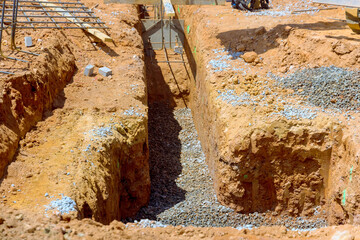Construction workers prepare trenches filled with gravel for building foundations in rural area...