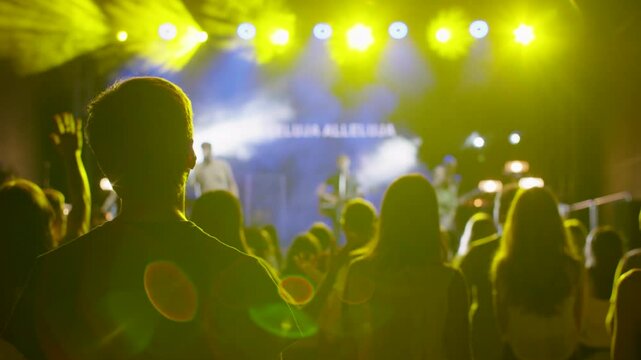 Calm worship scene with people standing, singing in soft light, and blurred musicians and lyrics on stage in the background. Ideal for faith content, church visuals, or peaceful spiritual gatherings