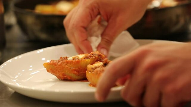 Chef stirs seasoned minced meat. Stuffed pasta shells with meat filling simmer in bubbling tomato sauce. This hearty, delicious Italian meal is perfect for a family dinner.