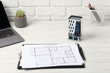 Real estate. Apartment building model, floor plan and laptop on white wooden table, closeup