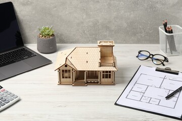Real estate. House model, floor plan and laptop on white wooden table