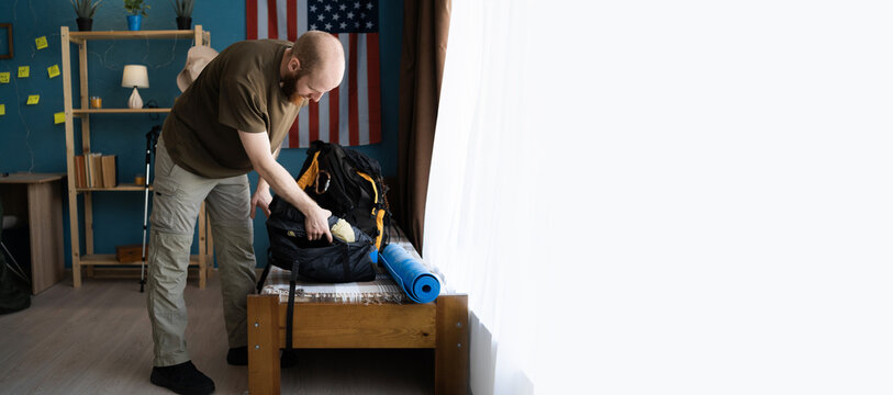 Tourist traveler preparing for a hike in the mountains packing a backpack in the bedroom at home - Powered by Adobe