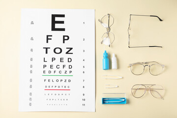 Vision test chart, glasses, tweezers and bottles of medical drops on beige background, flat lay