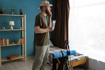 tourist traveler holds tickets and passport calls books hotel or taxi uses smartphone standing in...
