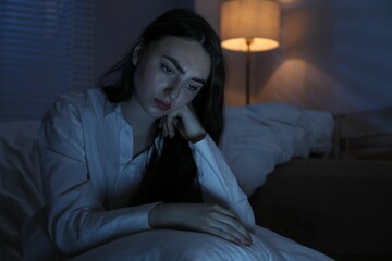 Frustrated woman with pillow suffering from insomnia on floor at home, space for text