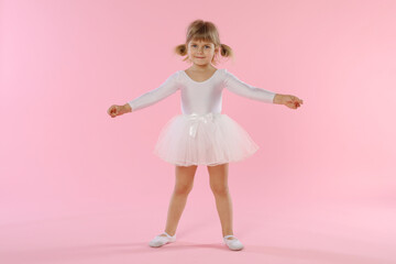 Cute little girl dancing on pink background