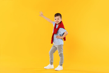 Happy little boy dancing on orange background
