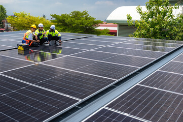 Group of photovoltaic engineer men working together inspecting solar panels on building roof