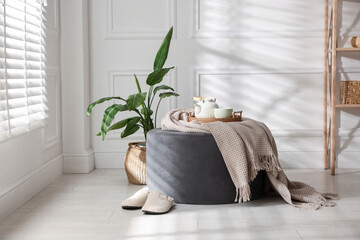 Stylish pouf with tea set at home