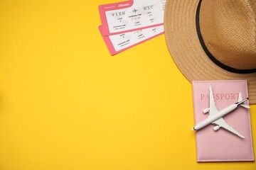 Passport, airplane model, hat and tickets on yellow background, flat lay. Space for text