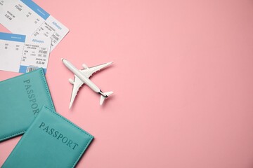 Passports with tickets and airplane model on pink background, flat lay. Space for text
