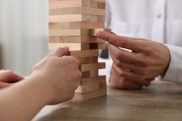 Lviv, Ukraine - December 19, 2023: People playing Jenga tower at wooden table indoors, closeup