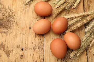 Fresh eggs and spikes on wooden table, flat lay. Space for text