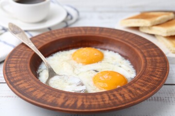 Half-boiled eggs in plate, spoon and toasted bread on white wooden table, closeup. Traditional asian breakfast