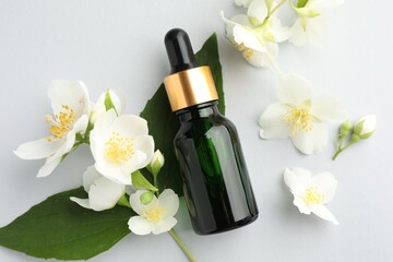 Cosmetic product and jasmine flowers on light background, flat lay