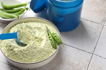 Protein powder and green peas on light tiled table, closeup