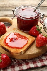 Tasty strawberry jam in glass jar, toast and fresh berries on table, closeup