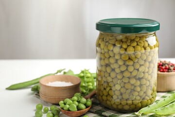 Tasty pickled peas in jar and ingredients on white table, closeup