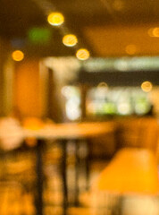 Intentionally blurred image of a cozy cafe interior with warm ambient lighting and bokeh effect,...