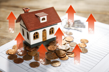 Increase in real estate value. House model and coins on table. Growing price represented by arrows...