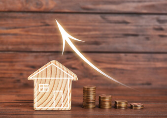 Increase in real estate value. House model and coins on table. Growing price represented by arrow