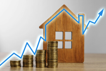 Increase in real estate value. House model and coins on table. Growing price represented by arrow