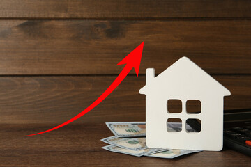 Increase in real estate value. House model and money on table. Growing price represented by arrow