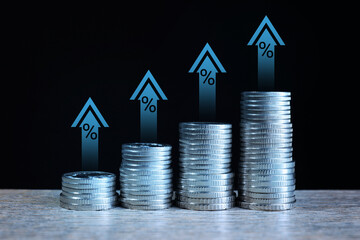 Increase in real estate value. Stacked coins on table. Growing price represented by arrows and...
