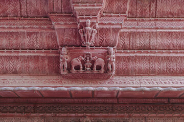 View of intricate carvings of elephants and figures adorn the textured, red sandstone architecture, a testament to timeless artistry, Bikaner, Rajasthan, India.