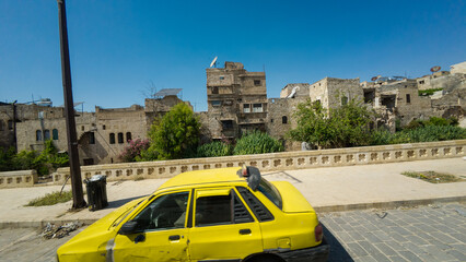 Yellow Taxi Passing Ancient Stone Buildings. Aleppo, Syria