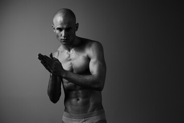 Muscular man in black and white, showcasing strength and determination, poses with clenched hands...