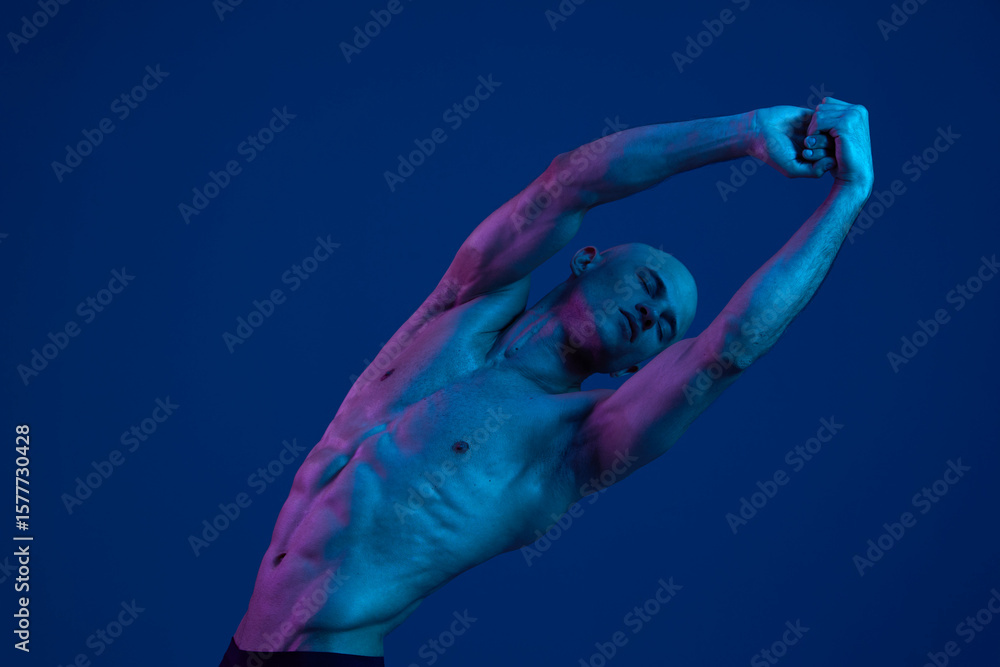 Poster strong man stretching under colorful light, showcasing well-defined muscles and an expressive pose. 