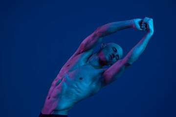 Strong man stretching under colorful light, showcasing well-defined muscles and an expressive pose....