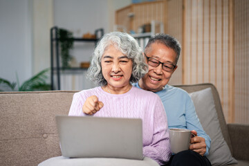 Asian Older Couple Using Laptop Computer on Couch Together Happy Asian Elderly Lifestyle Seniors Enjoying Technology Communication and Leisure Time