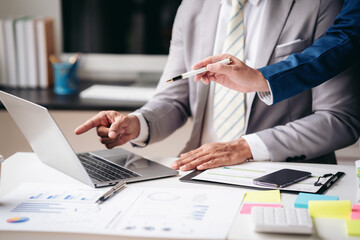 Two men are working on a laptop together