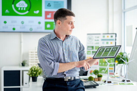 Adult business professional analyzing environmental social governance data on tablet for sustainable corporate strategy