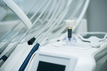 Close-up of dental chair instruments and a model of a dental implant on top