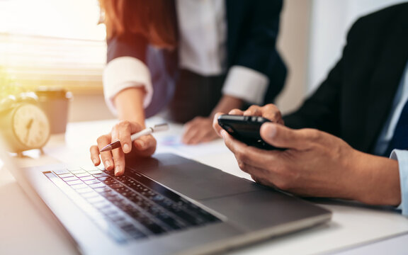 Two people are looking at a laptop and cell phones - Powered by Adobe