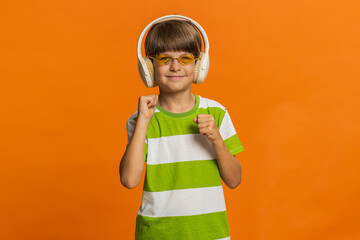 Happy smiling preteen child boy in headphones listening music dancing disco fooling around having...
