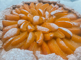 Delicious galette with bright juicy orange apricot slices generously dusted with powdered sugar