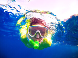 Naklejka premium Portrait of a woman in a mask with a snorkel floating underwater in the sea