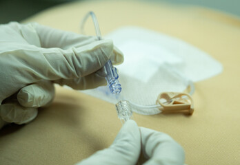 Sterile-gloved hands connecting a gripper (Huber) needle directly to IV tubing. Used in port-a-cath...