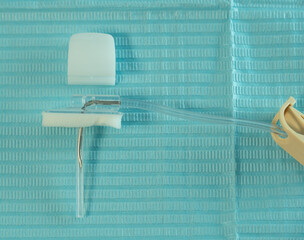Close-up of a Huber (gripper) needle with an adjacent safety clamp placed on a sterile blue drape....
