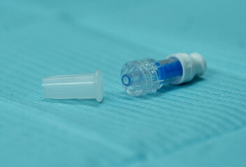 Naklejka premium Close-up rear view of a non-return injection cap with its protective cover placed nearby. Medical connector component used in IV therapy, port-a-cath systems, and catheter sealing.