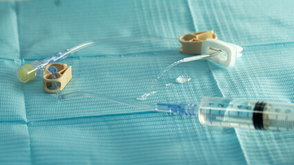 Sterile flushing of a Huber (gripper) needle set on a blue drape. Clear fluid exits the extension...