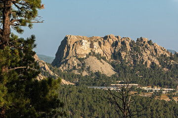 Mount Rushmore in the background with evergreen trees, and buildings in the foreground. Black Hills...