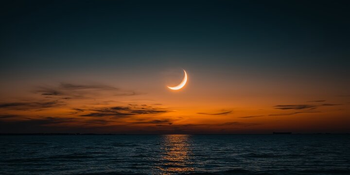 Soft Glowing Crescent Moon over Ocean at Sunset.
