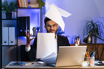 Stressed Indian businessman working looking at unpaid bank debt bills, doing paperwork, planning...