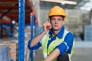 Warehouse, worker and working concept. Male warehouse worker working and management by radio walkie talkie in warehouse